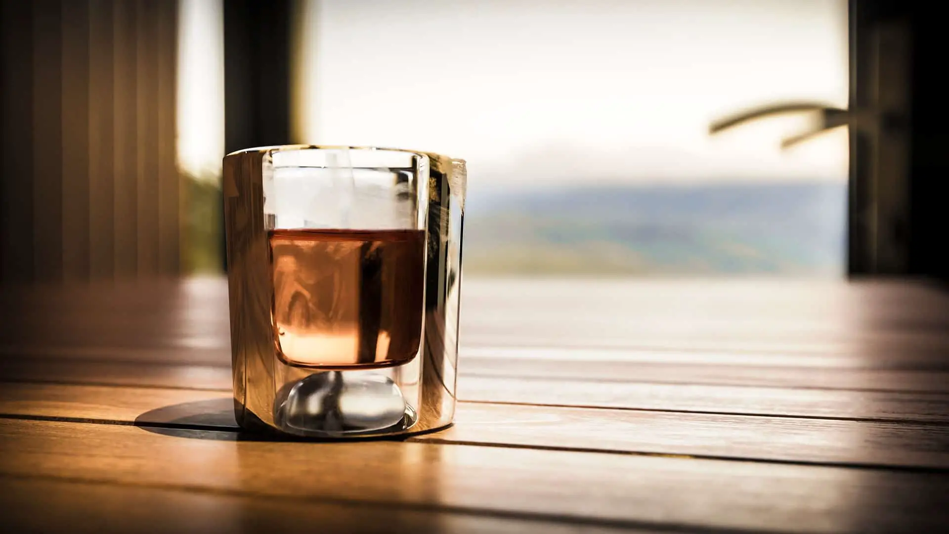 A glass of whiskey with an ocean view in the background