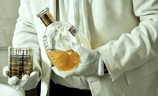 A butler serving whiskey from a decanter