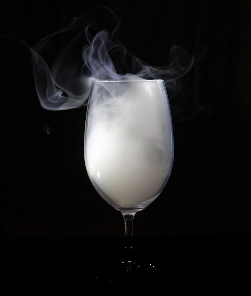 A whiskey glass with smoke billowing out