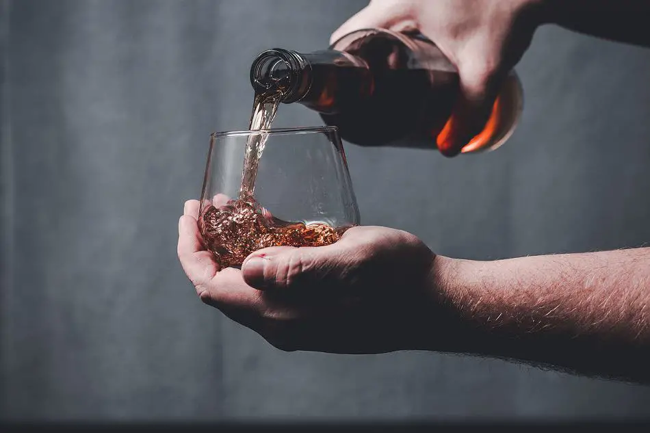 Pouring whiskey into a glass held in the palm of a hand