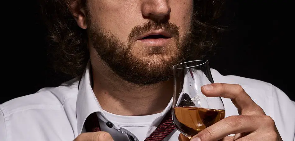 Man breathing while drinking a glass of whiskey