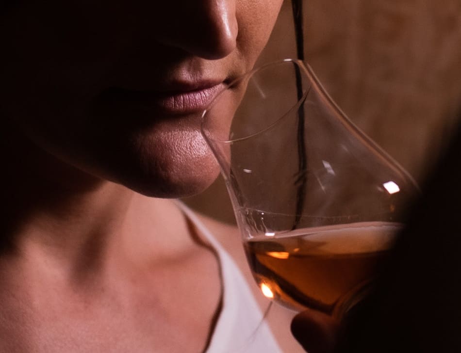 A person smelling whiskey in a nosing glass