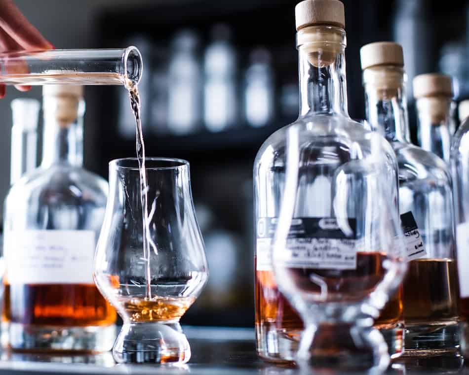 Water being poured into a glass of whiskey