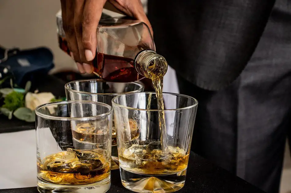 Man pouring lots of drinks of whiskey from a bottle