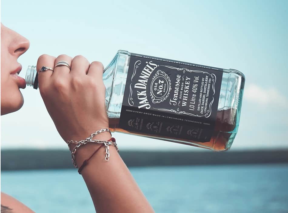 A person drinking out of a bottle of Jack Daniel’s