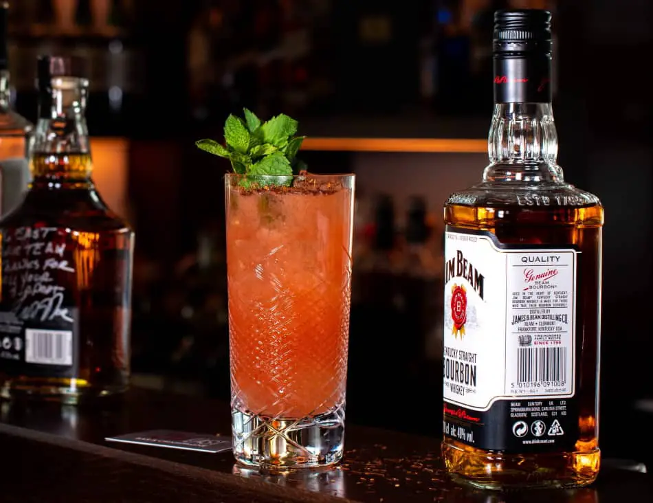 A bottle of Jim Beam and a cocktail on a bar counter