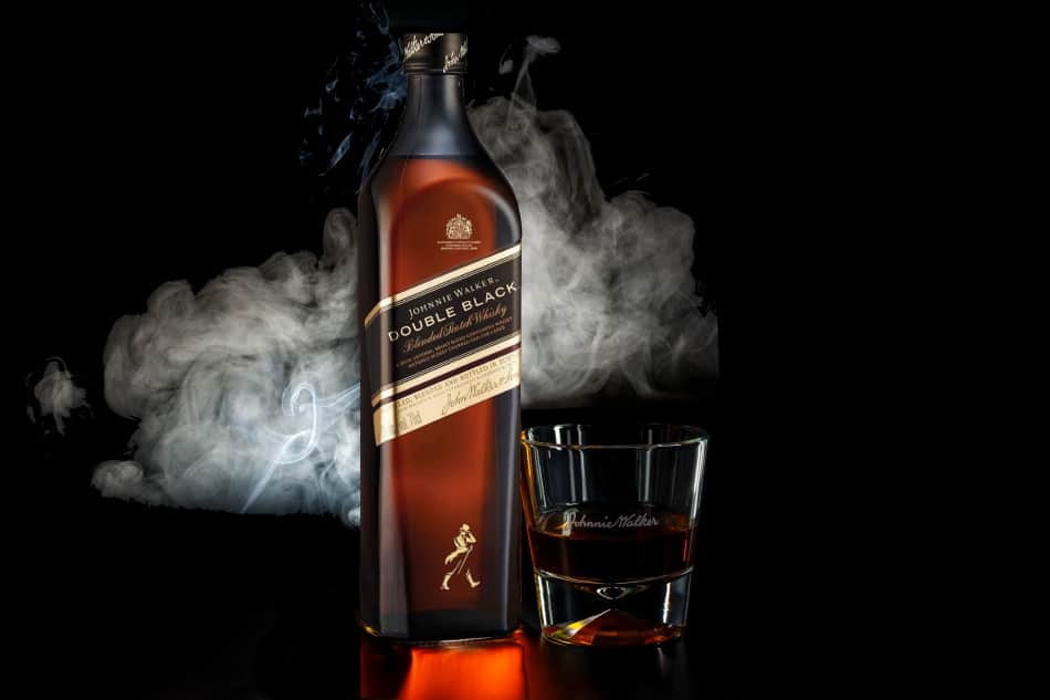 A bottle and glass of Johnny Walker Double Black surrounded by smoke