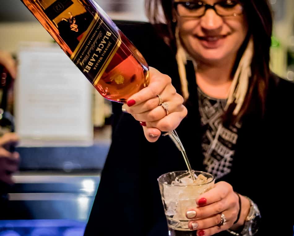 Woman pouring Johnny Walker Black Label into a cocktail