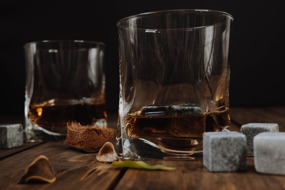 Two whiskey glasses surrounded by whiskey stones