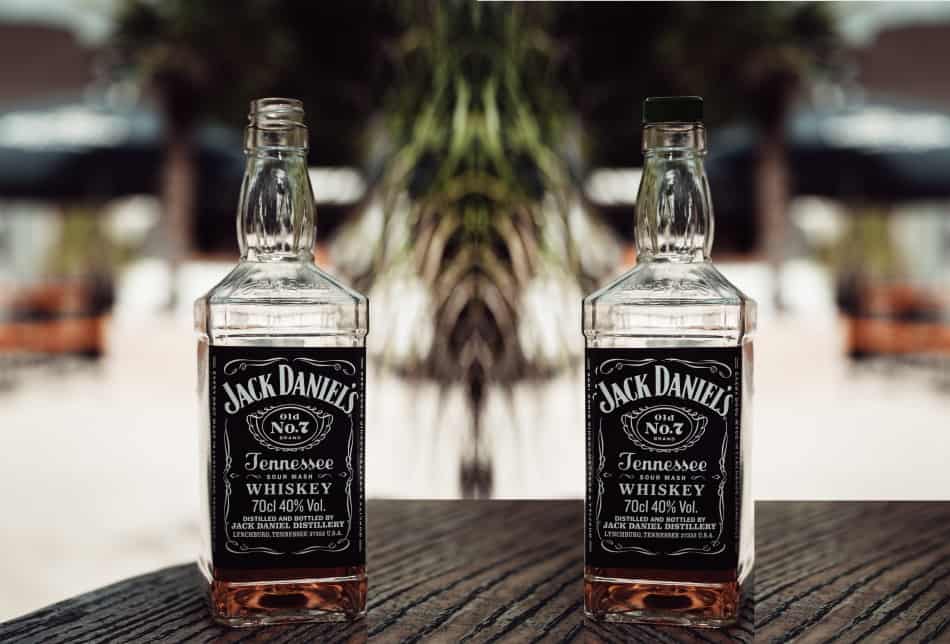 A bottle of Jack Daniel’s with no lid and a bottle of Jack Daniel’s with its lid on tight