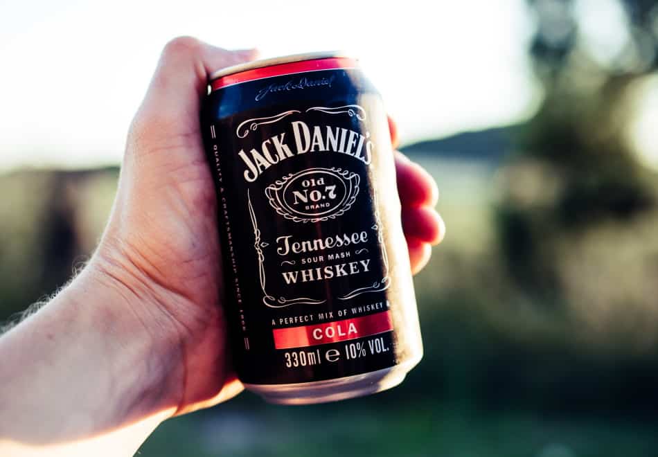 A hand holding a can of Jack Daniel’s and cola