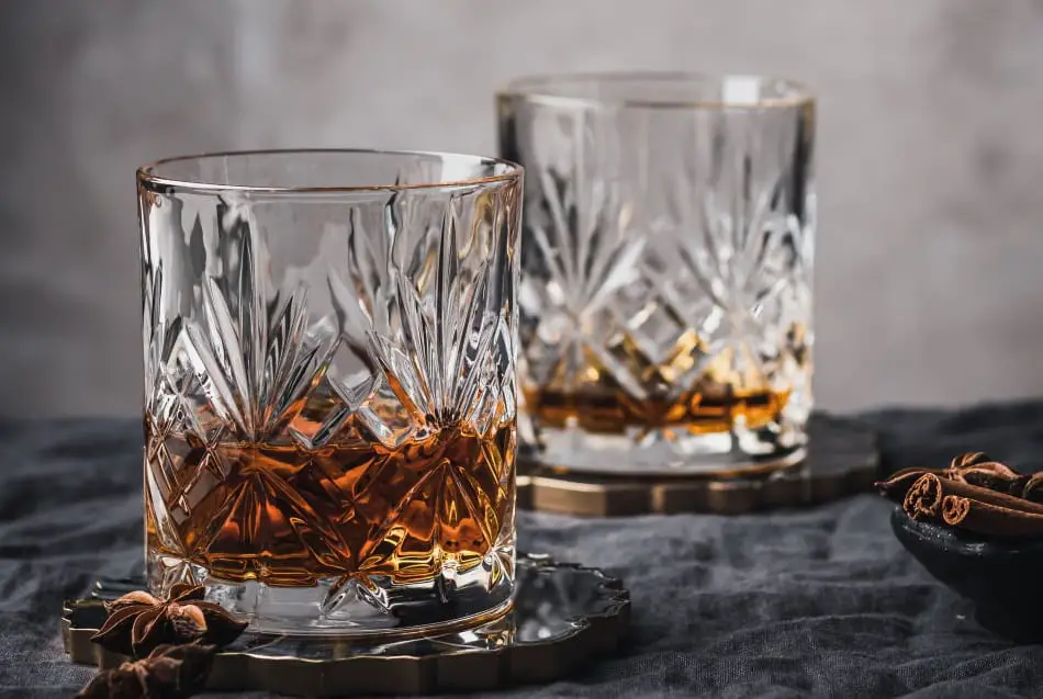 A glass with a small amount of whiskey and a glass with a large amount of whiskey