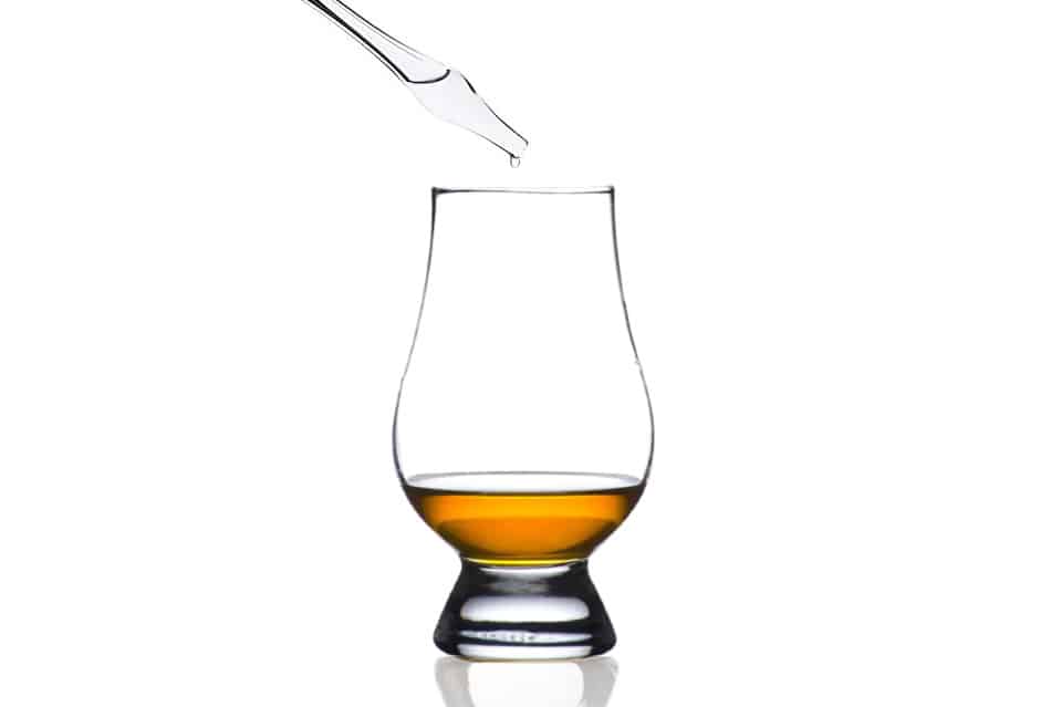 A water dropper dropping a drop of water into a Glencairn Whisky Glass