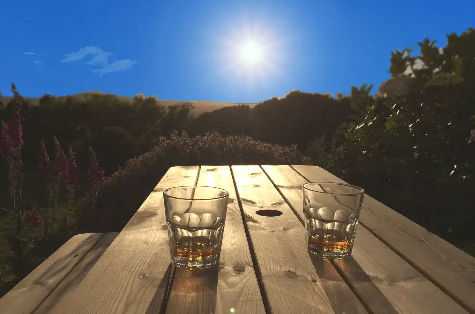 2 glasses of whiskey on a table in the sun