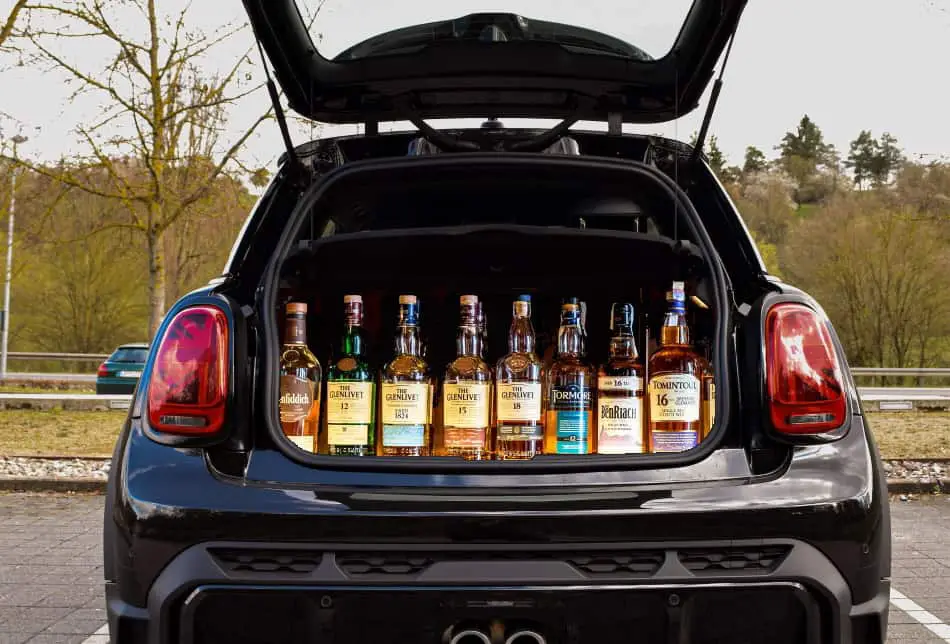Lots of whiskey bottles in the trunk of a car