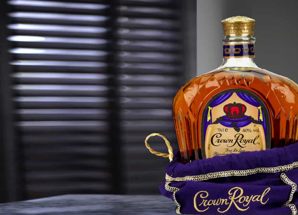 A bottle of Crown Royal in front of shutters that are protecting it from the sunlight